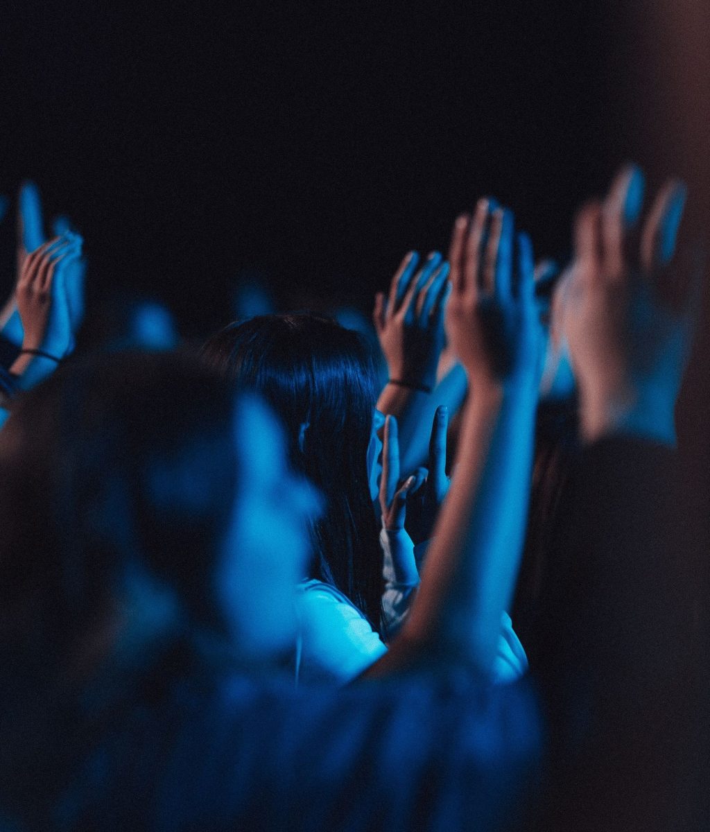 Vertical shot of believers in worship gathered in a hall with blue light effect